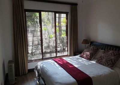 The master bedroom that looks out onto a private, shaded garden in the Sandton Gateway self-catering apartment in Craighall Park, Johannesburg.